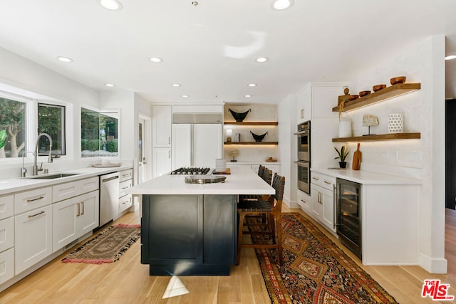 kitchen featuring light hardwood / wood-style floors, beverage cooler, a kitchen island, and appliances with stainless steel finishes