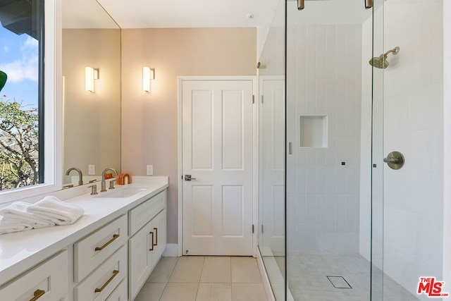 bathroom with vanity, a tile shower, and tile patterned flooring