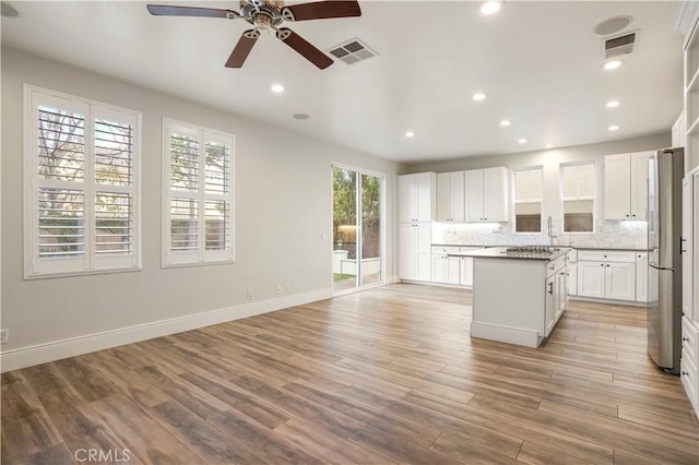 kitchen featuring white cabinetry, ceiling fan, decorative backsplash, a kitchen island, and light hardwood / wood-style flooring