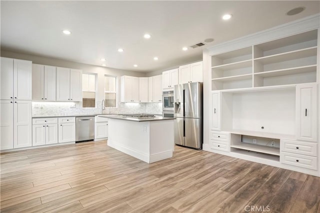 kitchen featuring white cabinets, light wood-type flooring, stainless steel appliances, and a center island