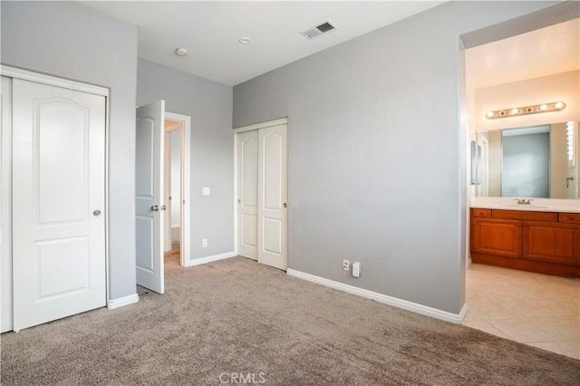 unfurnished bedroom with light colored carpet, connected bathroom, and sink