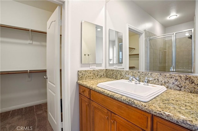 bathroom featuring a shower with shower door and vanity