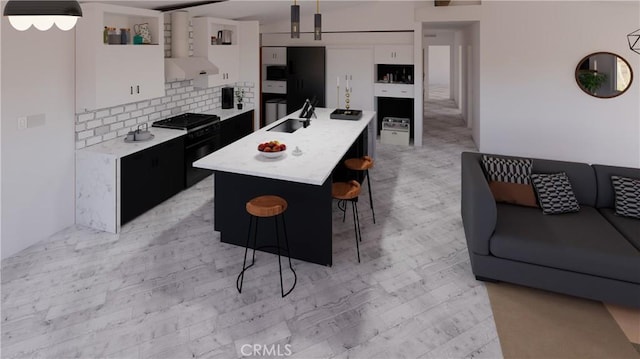 kitchen with sink, white cabinetry, decorative light fixtures, black range, and an island with sink