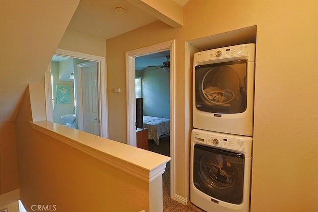 washroom featuring stacked washer and dryer, ceiling fan, and carpet