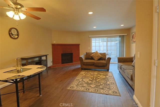 living room with ceiling fan, dark wood-type flooring, and a fireplace