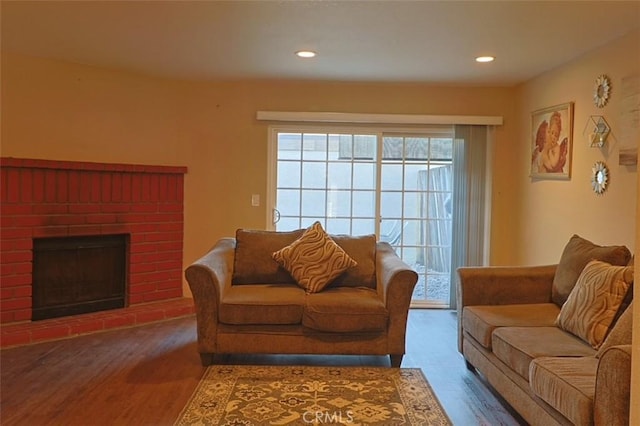 living room with hardwood / wood-style floors and a brick fireplace