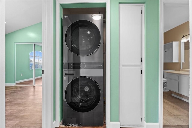 laundry room with stacked washing maching and dryer and light tile patterned flooring