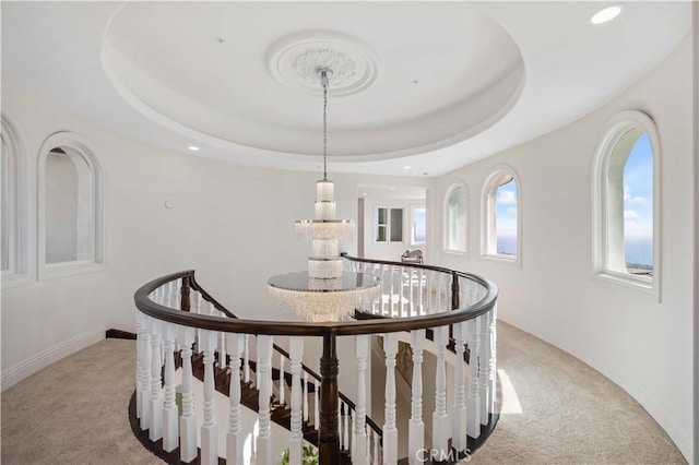 corridor with a raised ceiling and light colored carpet