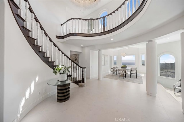 foyer entrance with a towering ceiling, ornate columns, and a notable chandelier