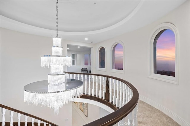 interior space with carpet floors, a raised ceiling, and a notable chandelier