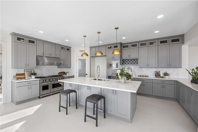 kitchen featuring decorative light fixtures, a kitchen island with sink, sink, and stainless steel appliances