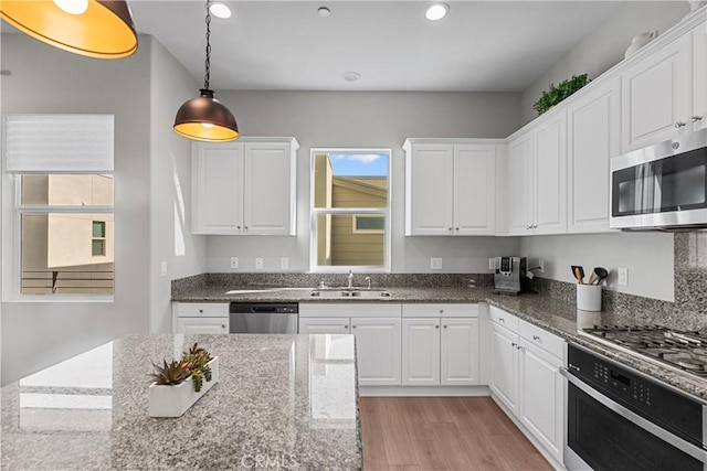 kitchen featuring appliances with stainless steel finishes, sink, dark stone countertops, and white cabinets