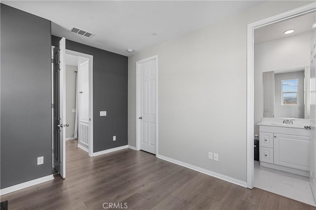 unfurnished bedroom with connected bathroom, dark hardwood / wood-style floors, and sink