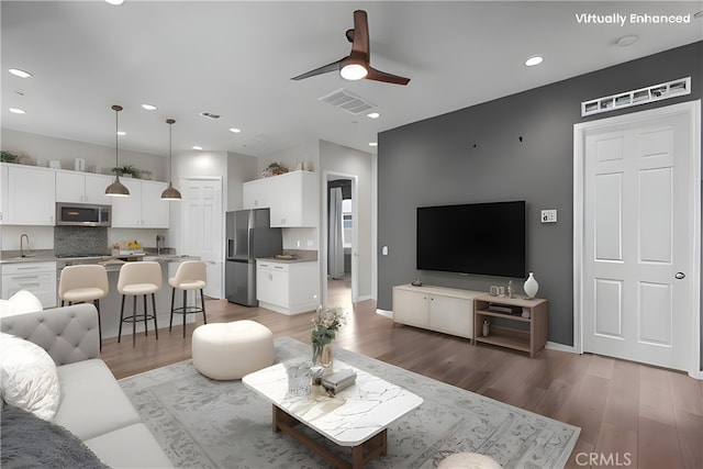 living room featuring sink, wood-type flooring, and ceiling fan