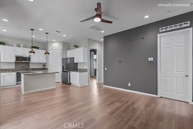 kitchen featuring an island with sink, white cabinets, hanging light fixtures, stainless steel appliances, and light hardwood / wood-style flooring