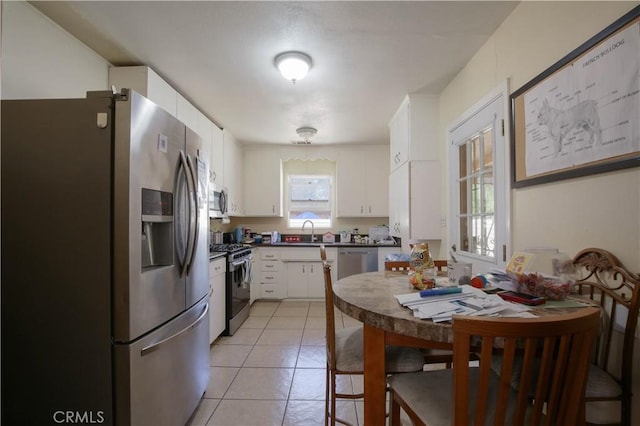 kitchen featuring light tile patterned floors, white cabinets, appliances with stainless steel finishes, and sink