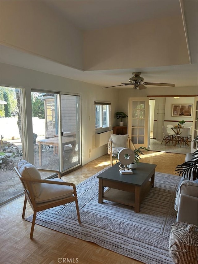 living room with ceiling fan, plenty of natural light, a towering ceiling, and light parquet flooring