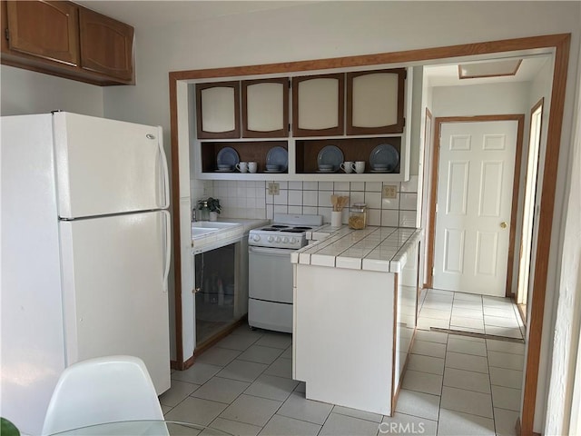 kitchen featuring decorative backsplash, white appliances, tile countertops, and light tile patterned flooring