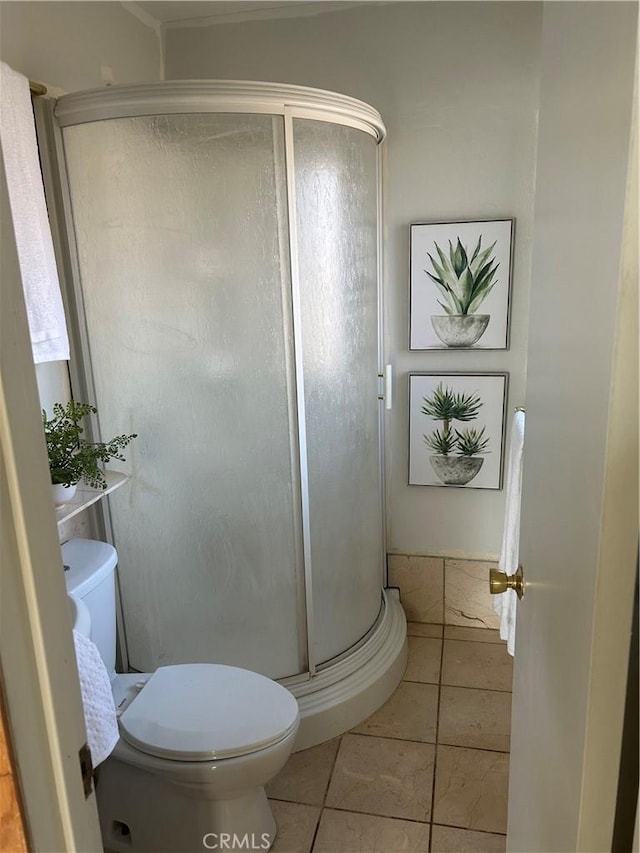 bathroom featuring toilet, tile patterned floors, and a shower with shower door