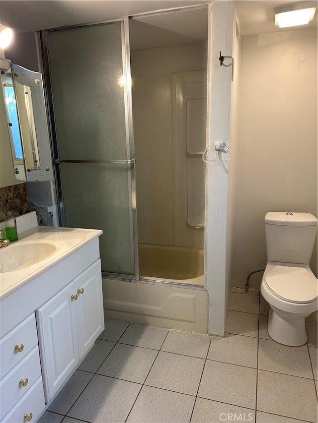 full bathroom with combined bath / shower with glass door, vanity, toilet, and tile patterned flooring