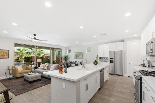 kitchen with ceiling fan, sink, white cabinetry, a kitchen island with sink, and appliances with stainless steel finishes