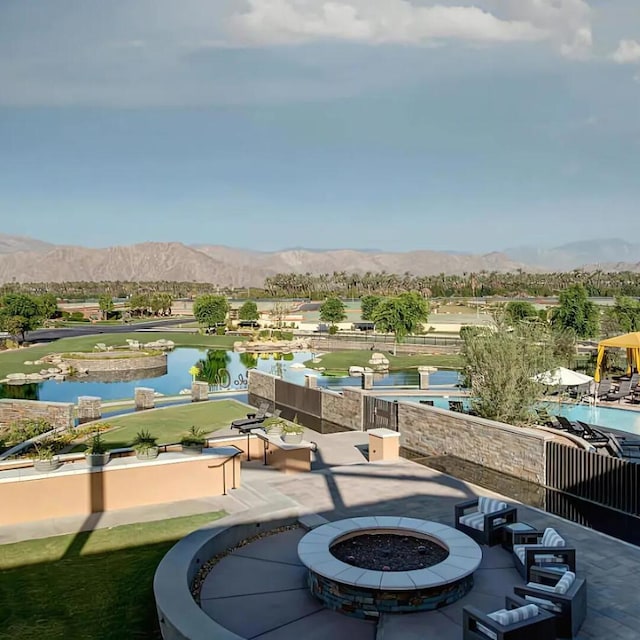 view of patio with a water and mountain view and a fire pit