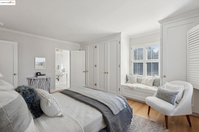 bedroom featuring connected bathroom, crown molding, and light wood-type flooring