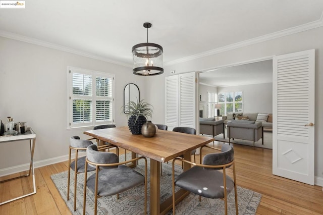 dining space featuring light wood-type flooring, crown molding, and an inviting chandelier