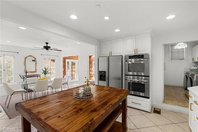 kitchen featuring separate washer and dryer, light tile patterned flooring, white cabinets, and appliances with stainless steel finishes