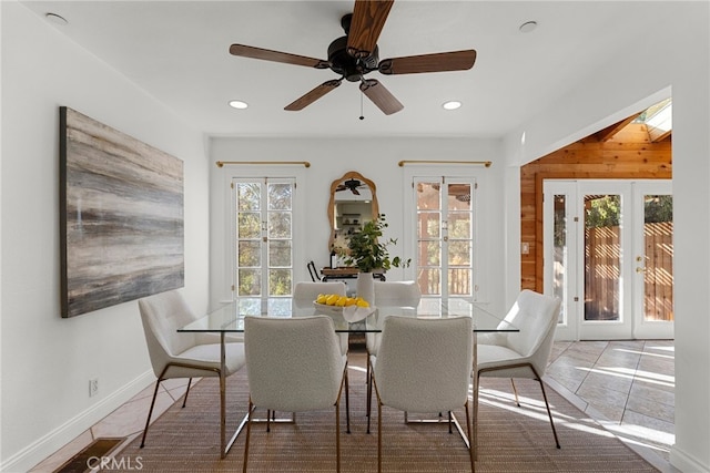 tiled dining space with a skylight, french doors, ceiling fan, and wood walls