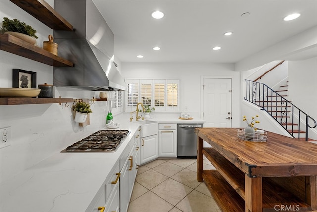 kitchen featuring island range hood, white cabinetry, sink, light tile patterned floors, and stainless steel appliances