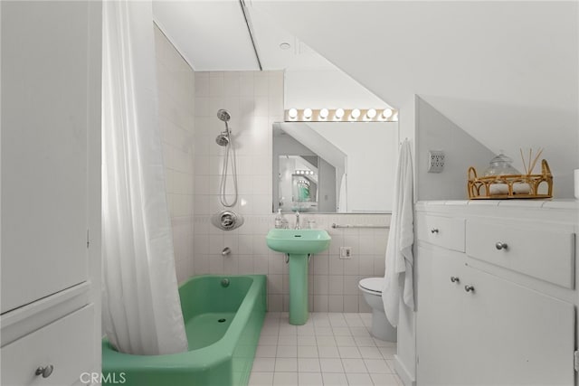 full bathroom with shower / tub combo with curtain, sink, tile patterned flooring, tile walls, and toilet