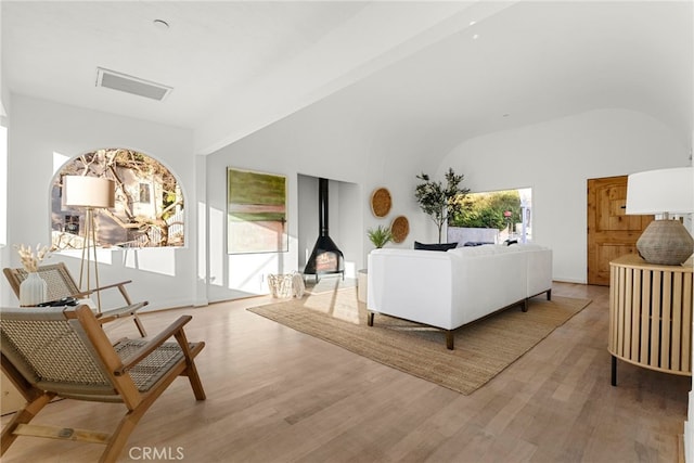 living room featuring hardwood / wood-style floors, beamed ceiling, and a wood stove