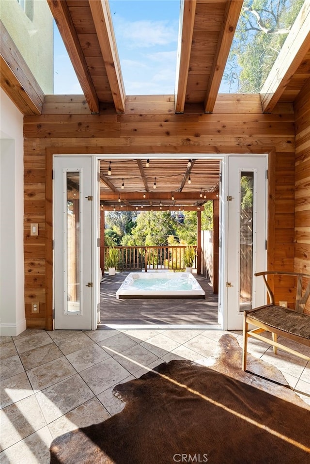 entryway with light tile patterned flooring, wooden walls, a skylight, and high vaulted ceiling