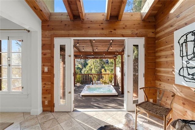 doorway featuring lofted ceiling with skylight, light tile patterned floors, and wood walls