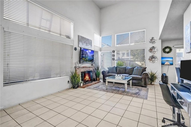 living room with a brick fireplace, a high ceiling, and light tile patterned floors