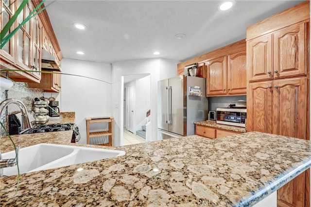 kitchen featuring light stone countertops, sink, stainless steel refrigerator, kitchen peninsula, and light tile patterned flooring