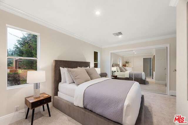 bedroom featuring light colored carpet, a closet, and ornamental molding