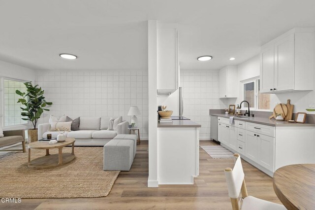 kitchen featuring tile walls, appliances with stainless steel finishes, white cabinetry, and light hardwood / wood-style flooring