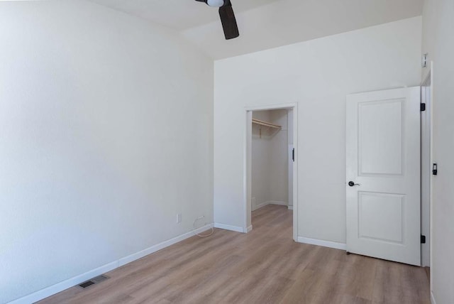 unfurnished bedroom with ceiling fan, lofted ceiling, light hardwood / wood-style floors, a spacious closet, and a closet