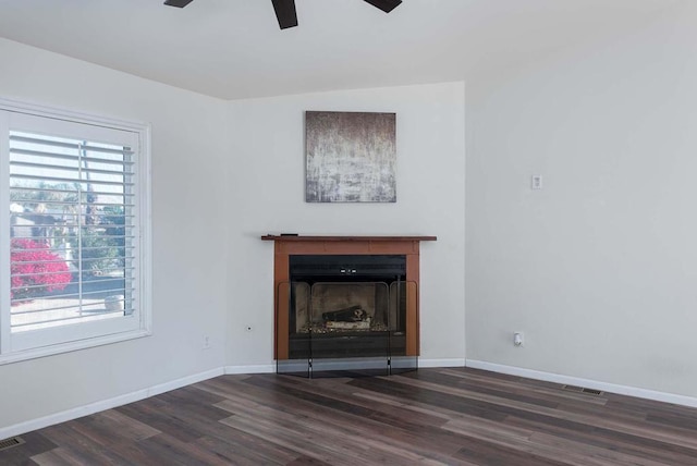 unfurnished living room with ceiling fan, a healthy amount of sunlight, and dark wood-type flooring