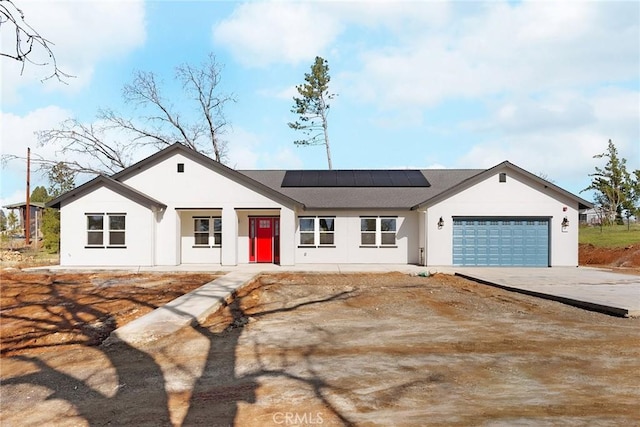 single story home with a garage and solar panels