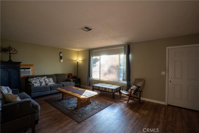 living room with dark hardwood / wood-style flooring and a wall unit AC