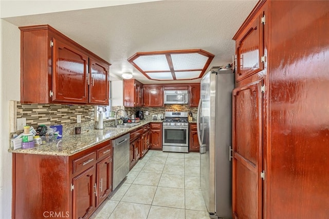 kitchen featuring appliances with stainless steel finishes, tasteful backsplash, light stone counters, and sink