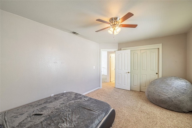 bedroom with ceiling fan, light colored carpet, and a closet