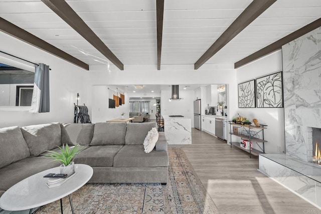 living room with vaulted ceiling with beams, wood ceiling, and light hardwood / wood-style flooring