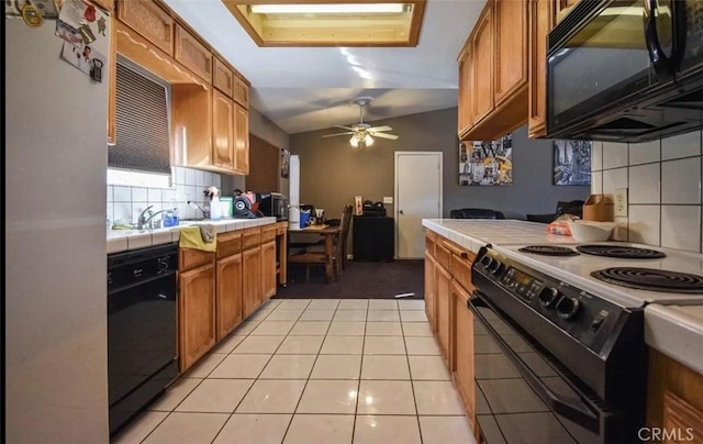 kitchen with tile countertops, a ceiling fan, vaulted ceiling, black appliances, and tasteful backsplash