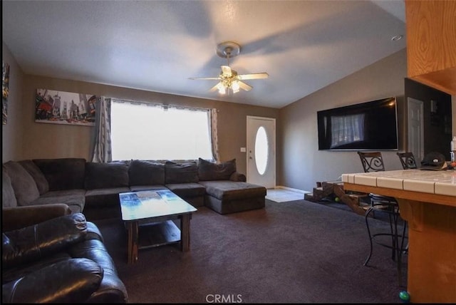 living area with dark colored carpet, vaulted ceiling, baseboards, and ceiling fan