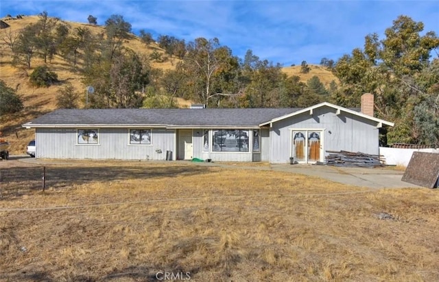 single story home featuring a chimney, a mountain view, and a front yard