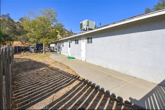 view of home's exterior with central AC, fence, and stucco siding